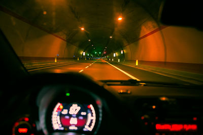 Cars in illuminated tunnel seen through car windshield