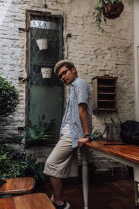 Portrait of young man sitting against wall