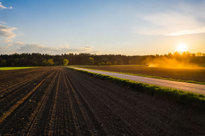 Scenic view of agricultural field against sky during sunset