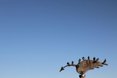 Low angle view of birds flying against clear blue sky