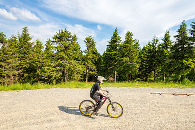 Man riding bicycle on street against sky