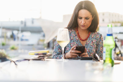 Mid adult woman using mobile phone on table