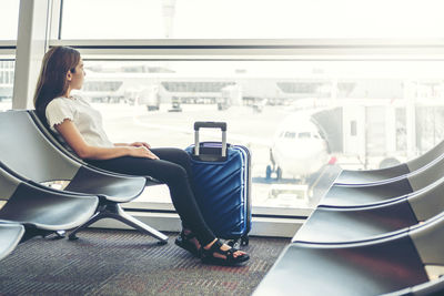 Side view of woman sitting on chair in airport