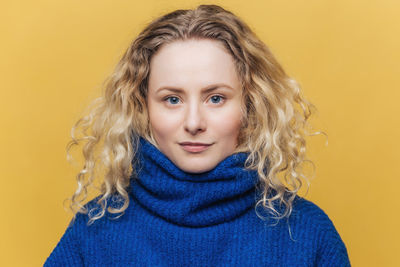 Portrait of young woman against yellow background