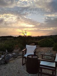 Chairs and table against sky during sunset