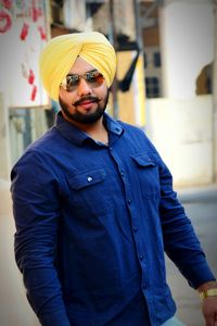 Portrait of young man wearing sunglasses while standing on footpath