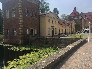 Canal by buildings in town against sky