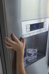 Cropped hand of child holding water purifying machine at home