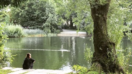 Man sitting by lake in forest