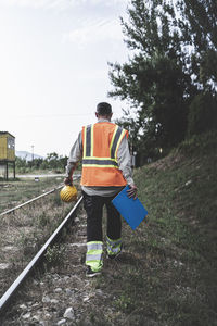 Rear view of worker walking by railroad track