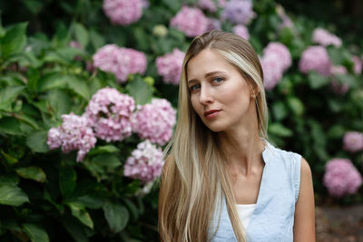 Portrait of young woman standing against plants