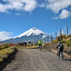 People riding bicycle on road against sky