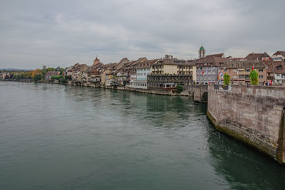 Buildings by river against sky