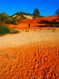 Distant view of man walking on sand dune in desert