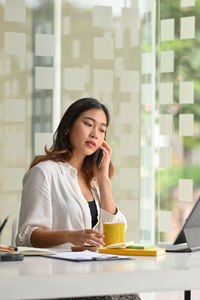 Young woman using mobile phone while sitting at office
