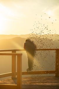 Surreal photograph of boy on wooden deck enjoying scenery in sunny day