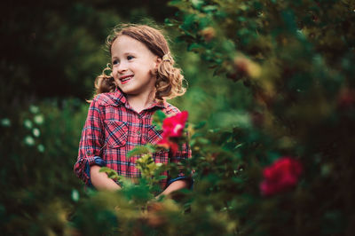 Portrait of smiling girl standing against plants