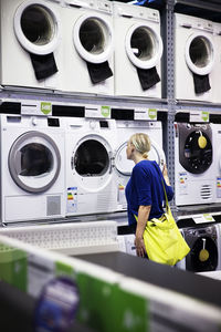 Woman looking at washing machines in shop