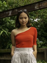 Portrait of beautiful woman standing against trees