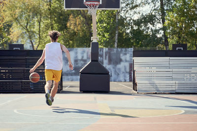 Rear view of man walking on basketball court