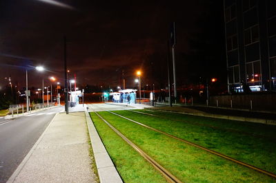 Illuminated railroad tracks against sky at night