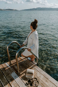 Side view of woman standing on ladder by sea