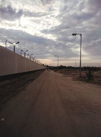 Empty road by street against sky during sunset