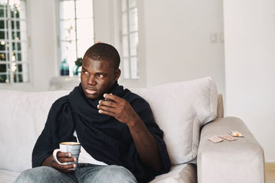 Young man sitting on sofa at home