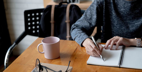 Midsection of man using mobile phone while sitting on table