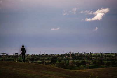 Rear view of man standing on field against sky
