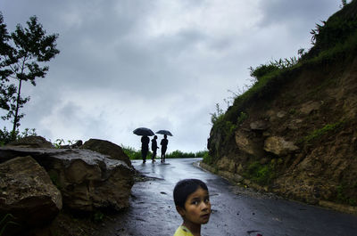 Boy looking away while standing on road