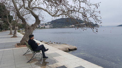 Side view of man sitting on bench