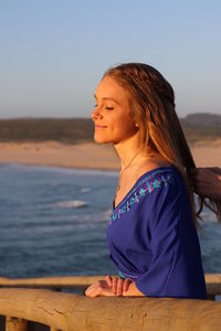 Young woman on beach against sky during sunset