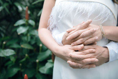 Midsection of newlywed couple holding hands