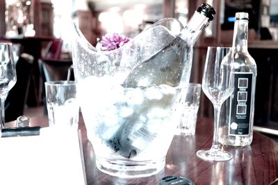 Champagne bottle in glass container on table at bar