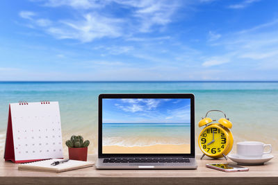 Wireless technology with office supplies on desk against beach