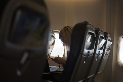 Businesswoman with sitting in airplane  and   using laptop,female working,business travel