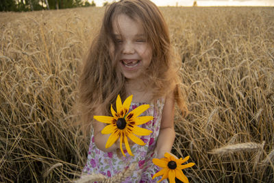 Close-up of smiling girl with yellow flower