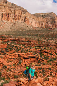 Side view of woman with backpack standing on landscape against mountain