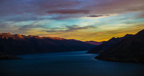 Scenic view of sea and mountains against dramatic sky