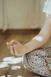 Midsection of woman sitting on bed at home