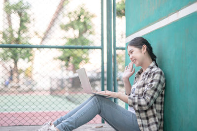 Side view of young woman using mobile phone outdoors
