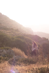 Rear view of woman standing on mountain against sky