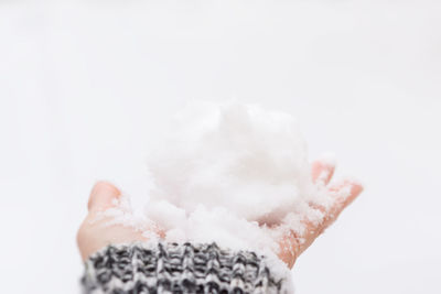 Close-up of hand holding snow over white background