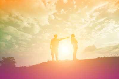 Silhouette friends standing against sky during sunset