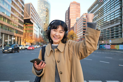 Portrait of young woman standing in city