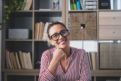 Portrait of smiling woman against book shelf