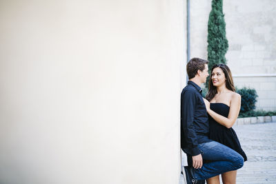 Young couple standing against wall