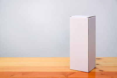 Empty wooden table against white wall