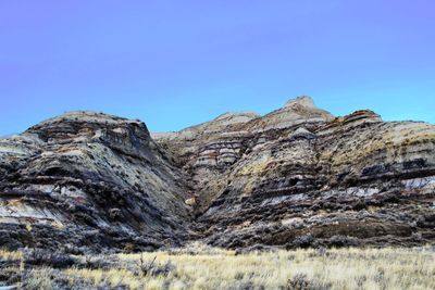 Low angle view of rocky mountains against clear blue sky